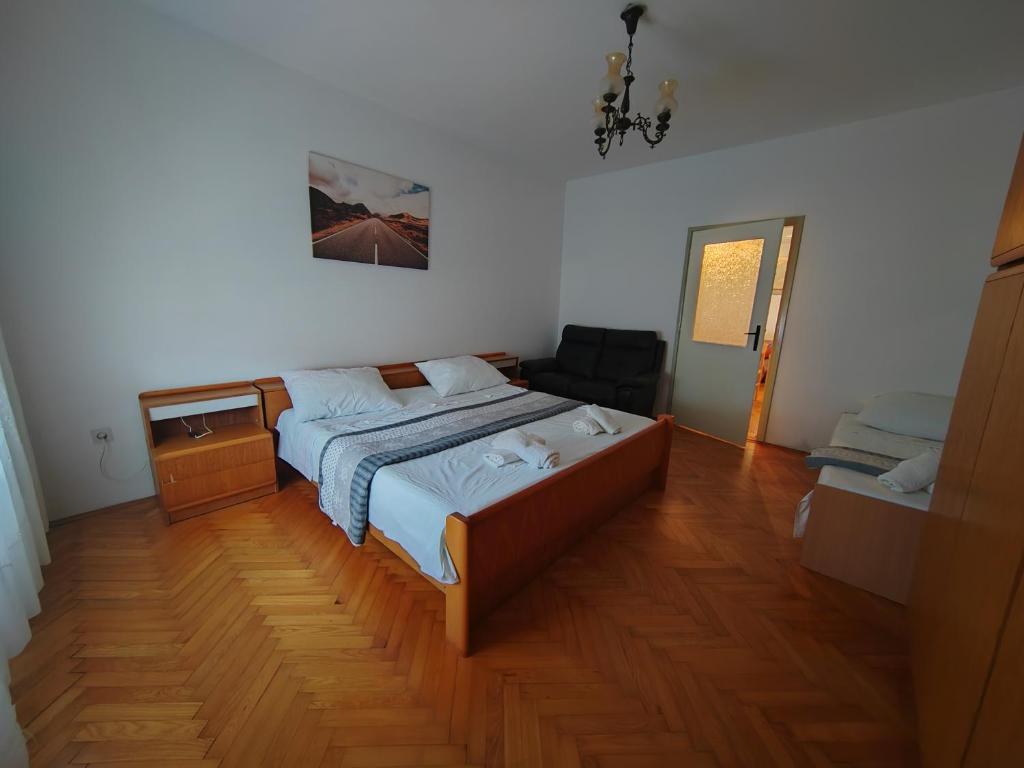 una camera con letto e pavimento in legno di Apartments Kocijan a Sukošan (San Cassiano)