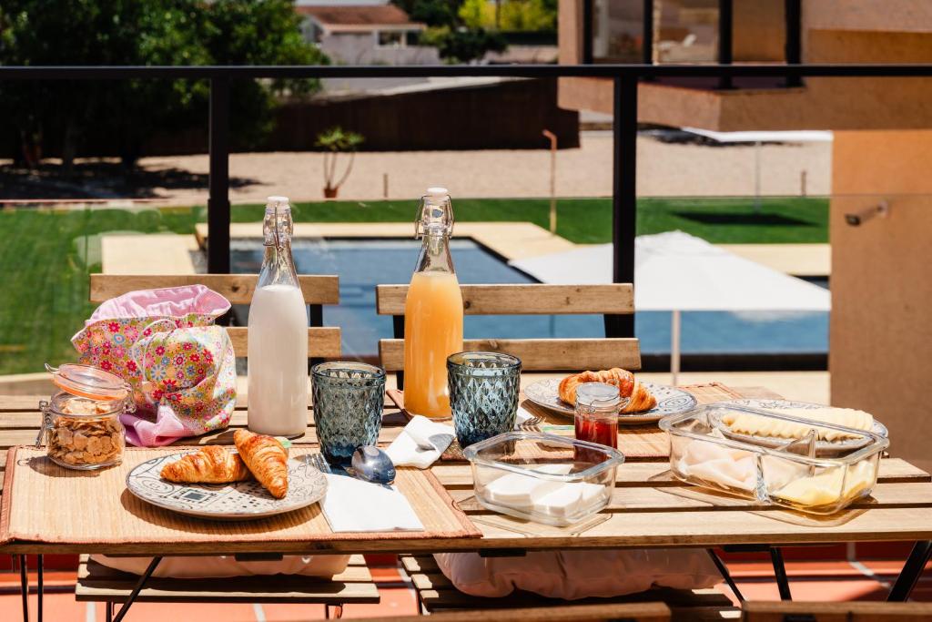 une table en bois avec des assiettes de nourriture et des bouteilles de lait dans l'établissement VILLA DOS R'S, à Aviz