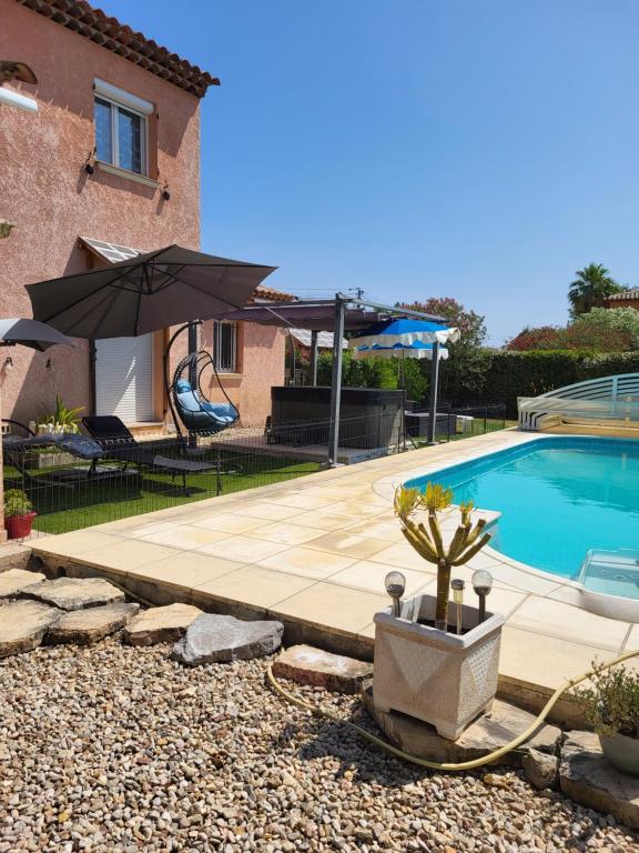 a house with a swimming pool and an umbrella at La Toscane in Roquebrune-sur-Argens