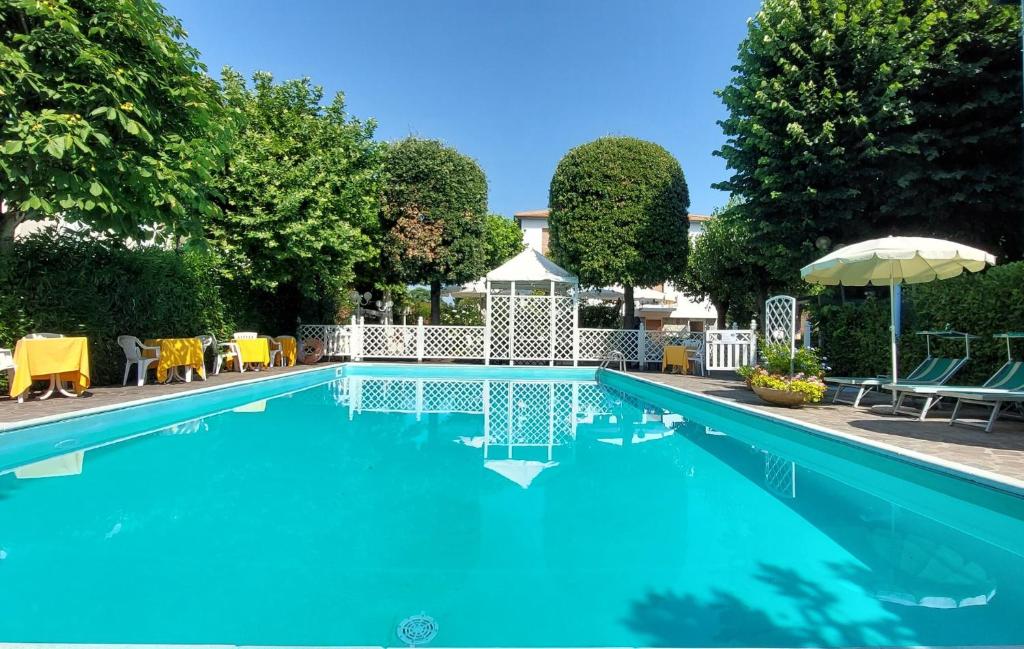 a blue swimming pool with chairs and an umbrella at Hotel Garden B&B in Marotta