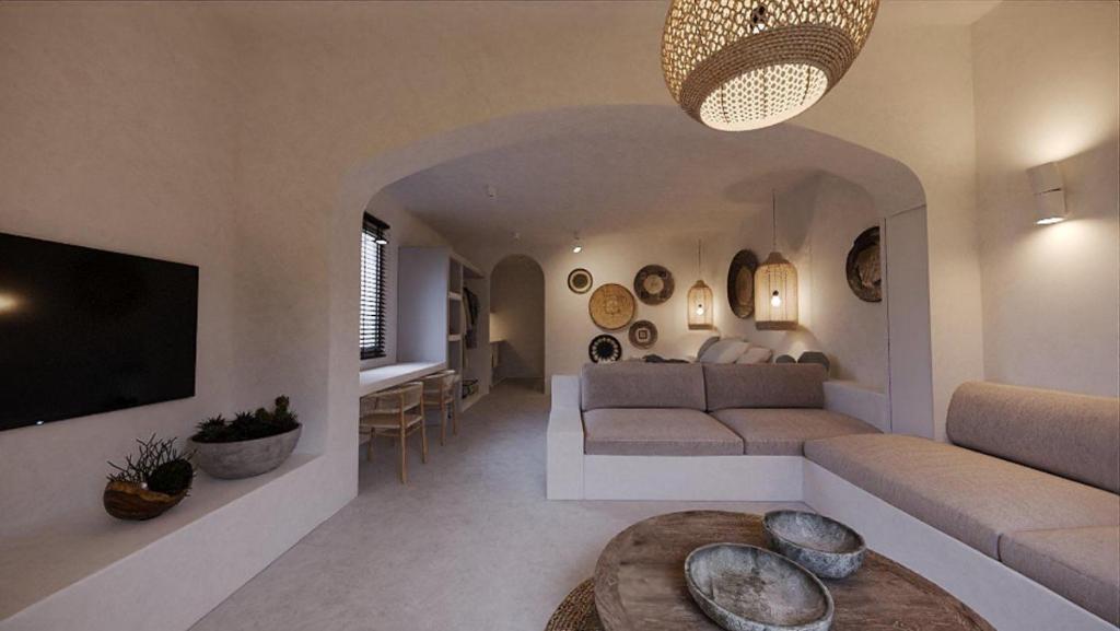 een woonkamer met een bank en een tv bij Lejardin suites santorini in Pirgos
