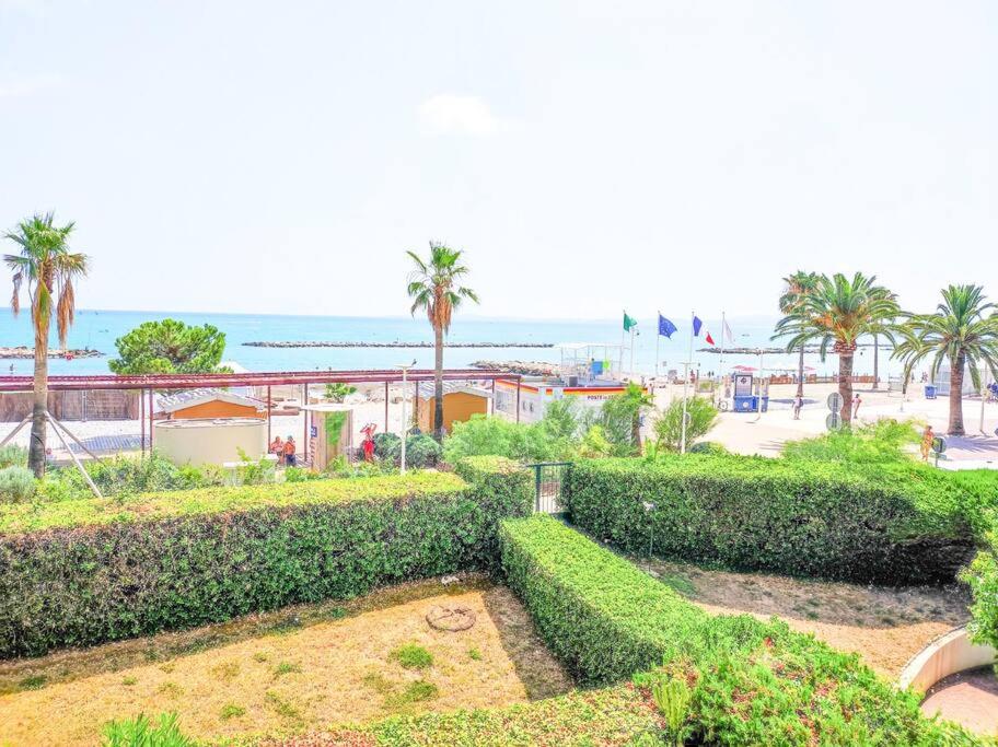 a park with bushes and palm trees and the beach at Horizon YourHostHelper in Saint-Laurent-du-Var