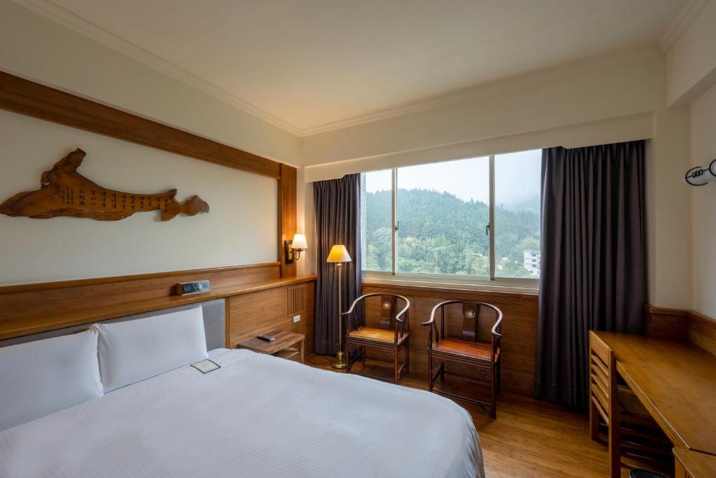 a hotel room with a bed and a desk and a window at Ginkgo Hotel in Lugu