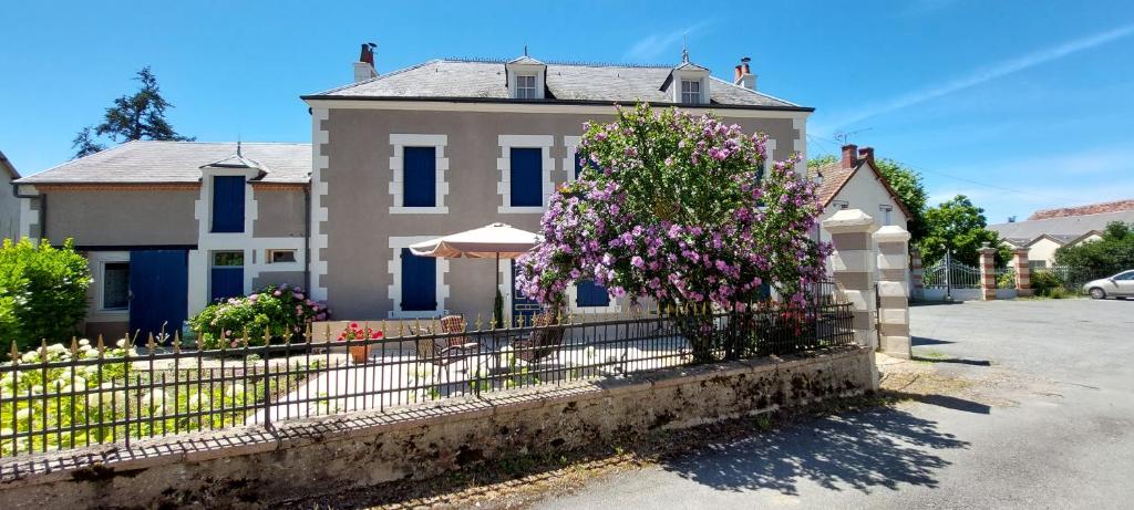 uma casa com uma cerca e flores à frente dela em Chambres d’hôtes La Joyeuse em Préveranges