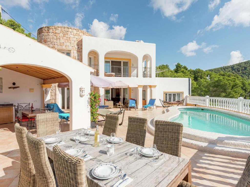 an external view of a villa with a table and a swimming pool at Belvilla by OYO Monte Perdido in Cala Llonga