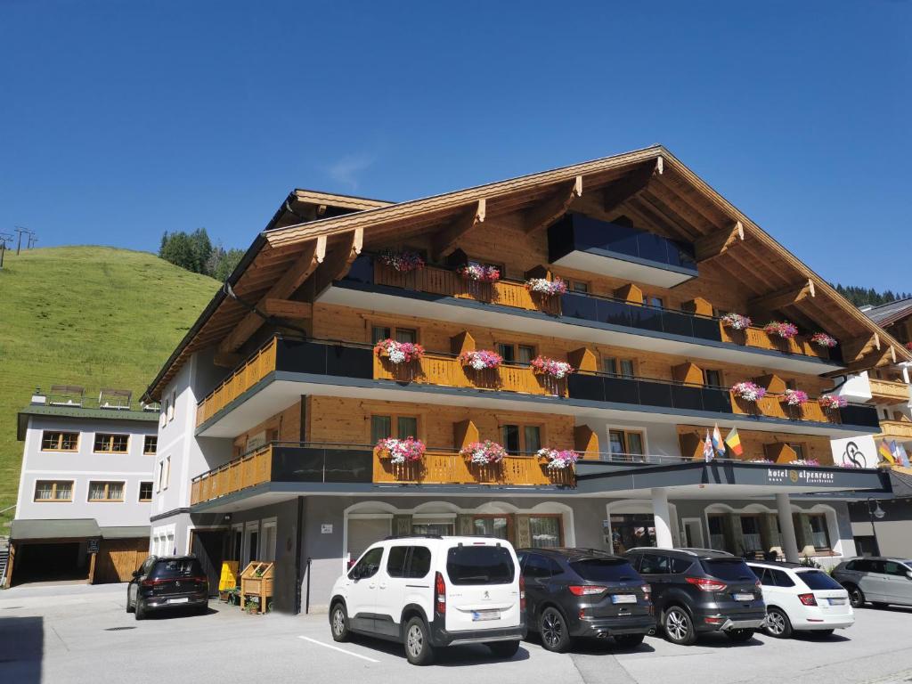 ein großes Gebäude mit Autos auf einem Parkplatz in der Unterkunft Hotel Alpenrose in Zauchensee