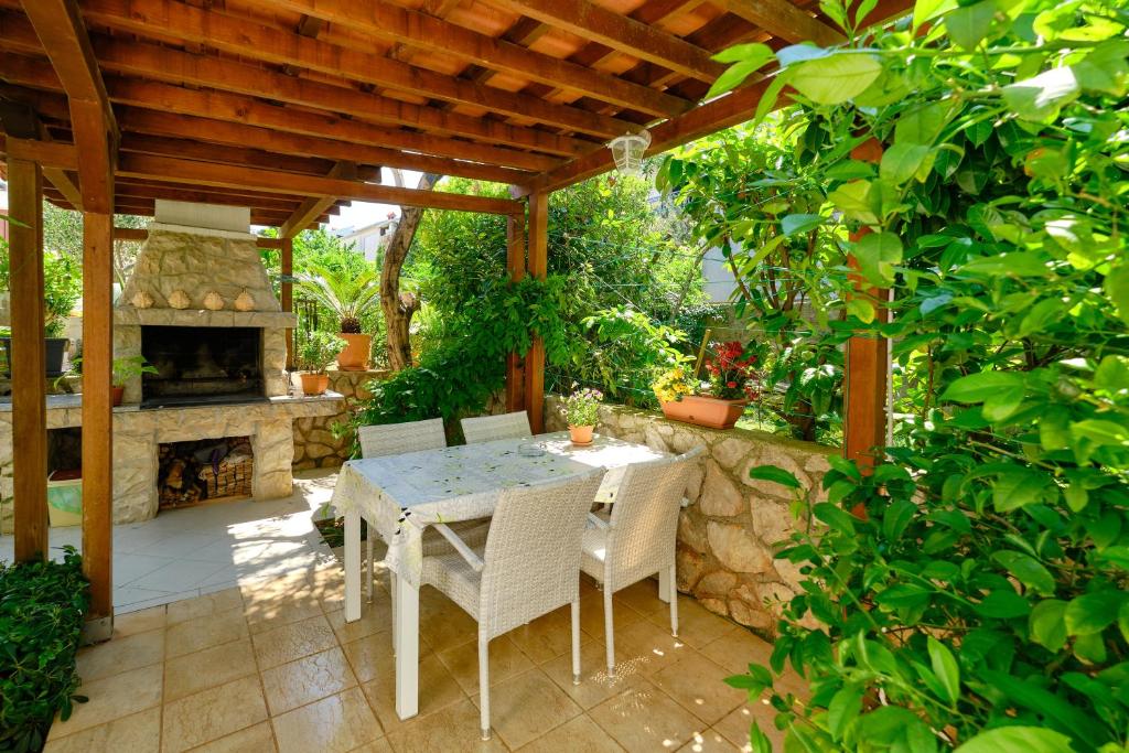 a patio with a table and chairs and a fireplace at Apartman Mirjana 1 in Mali Lošinj