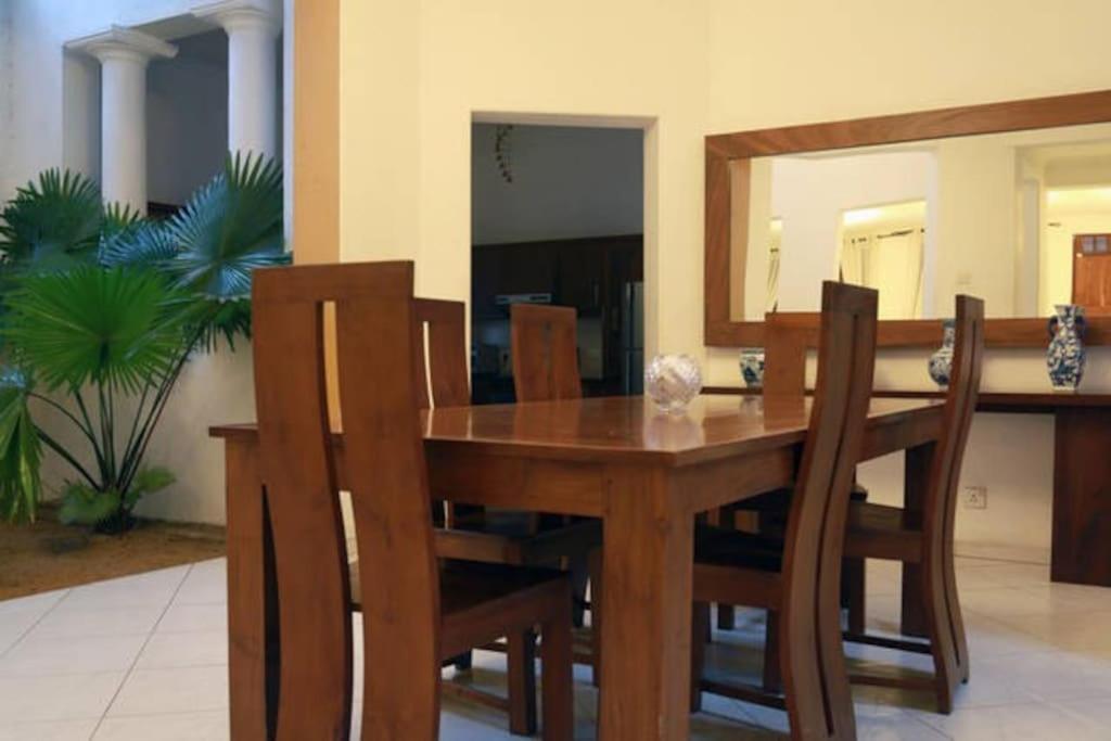 mesa de comedor de madera con sillas y espejo en Luxury Colombo Escape, en Talawatugoda