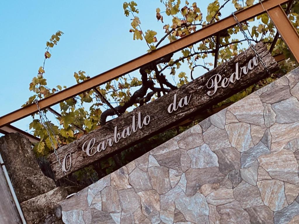 un cartello sopra un muro di pietra di Casa rural O CARBALLO DA PEDRA a La Cañiza