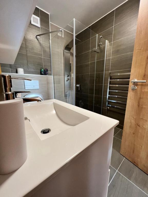 La salle de bains est pourvue d'un lavabo blanc et d'une douche. dans l'établissement Apartmán Roda2 Malé Lipno, à Černá v Pošumaví