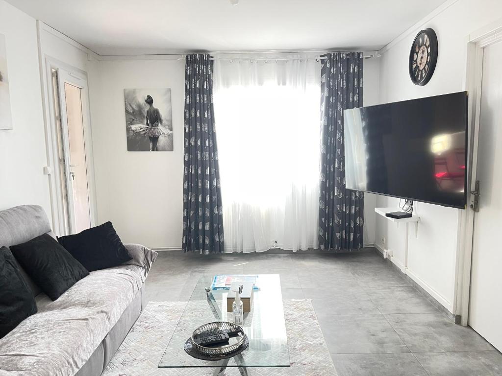 uma sala de estar com um sofá e uma televisão de ecrã plano em Eurexpo Lyon à 9 min ,Groupama Stadium à 14 min em Saint-Priest