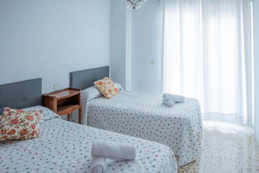 1 dormitorio con 2 camas, mesa y ventana en Apartamento Parque Mediterráneo, en Málaga