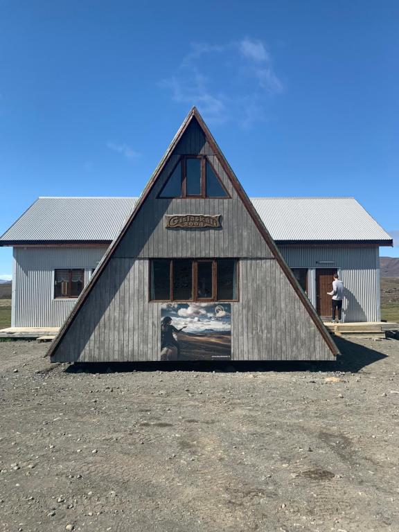 Un granero grande con un hombre parado frente a él. en Gíslaskáli, en Bergsstaðir