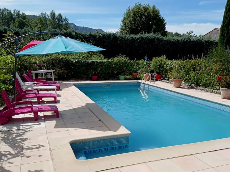 einen Pool mit 2 Stühlen und einem Sonnenschirm sowie einem Tisch und Stühlen sidx. in der Unterkunft maison piscine privée Robion Luberon idéal famille in Robion en Luberon