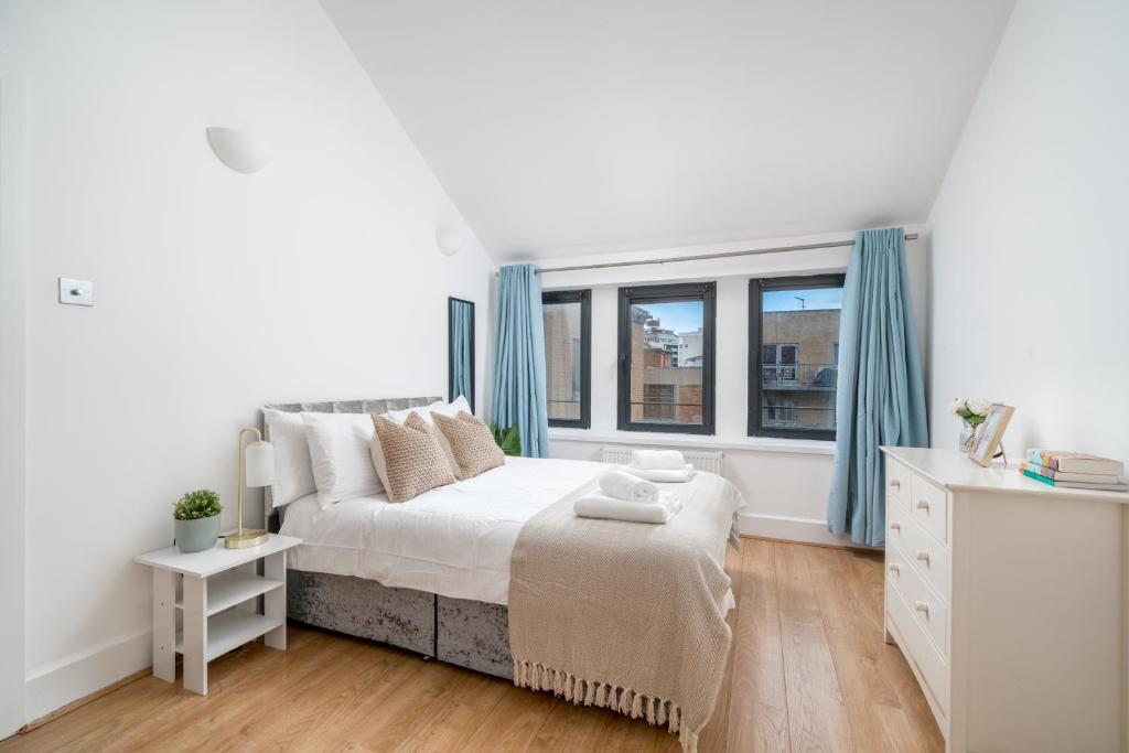 a white bedroom with a bed and a window at Modern 1 Bedroom City Penthouse Apartment in London