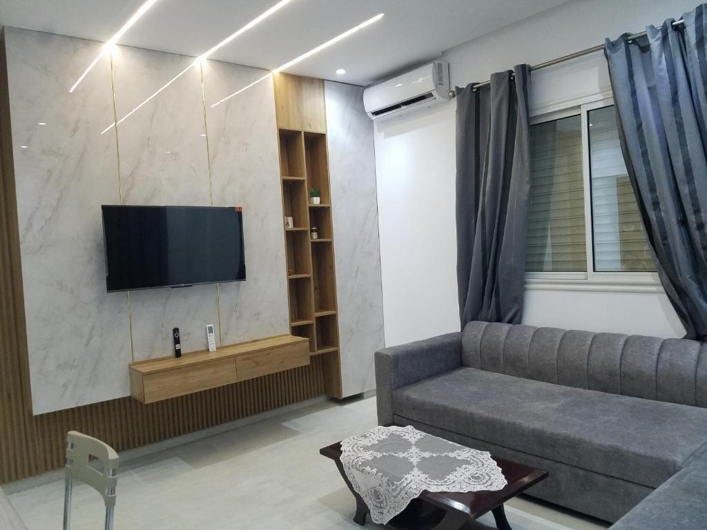 een woonkamer met een bank en een flatscreen-tv bij Joli Villa à Sahloul in Sousse