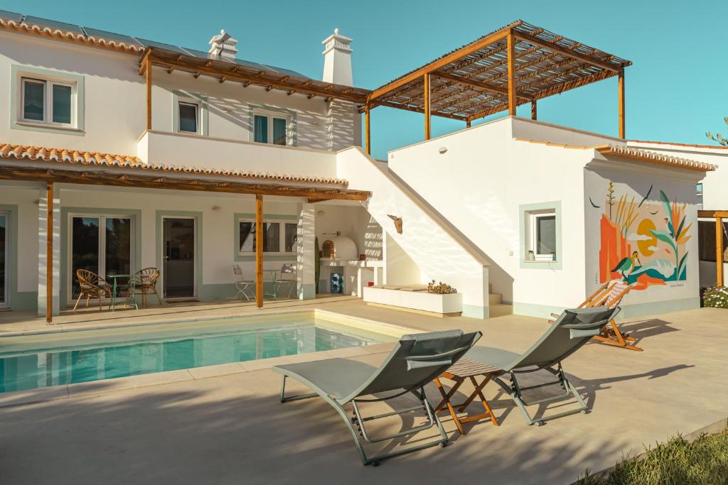 a villa with a swimming pool and two chairs at Birds of Paradise in Aljezur