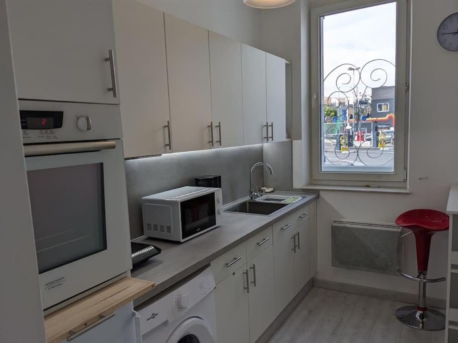 een keuken met witte kasten, een magnetron en een raam bij joli studio T2 meublé de 20 m² Située à 2 minutes à pied du MÉTRO in Marseille