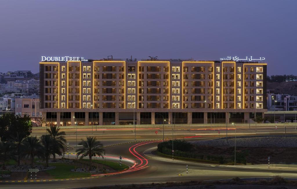 a large building with a road in front of it at DoubleTree by Hilton Muscat Qurum in Muscat
