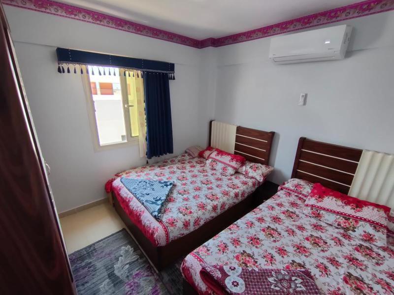 1 dormitorio con 2 camas y ventana en حجز شاليه غرفتين ورسيبشن بمارينا دلتا, en Al Ḩammād