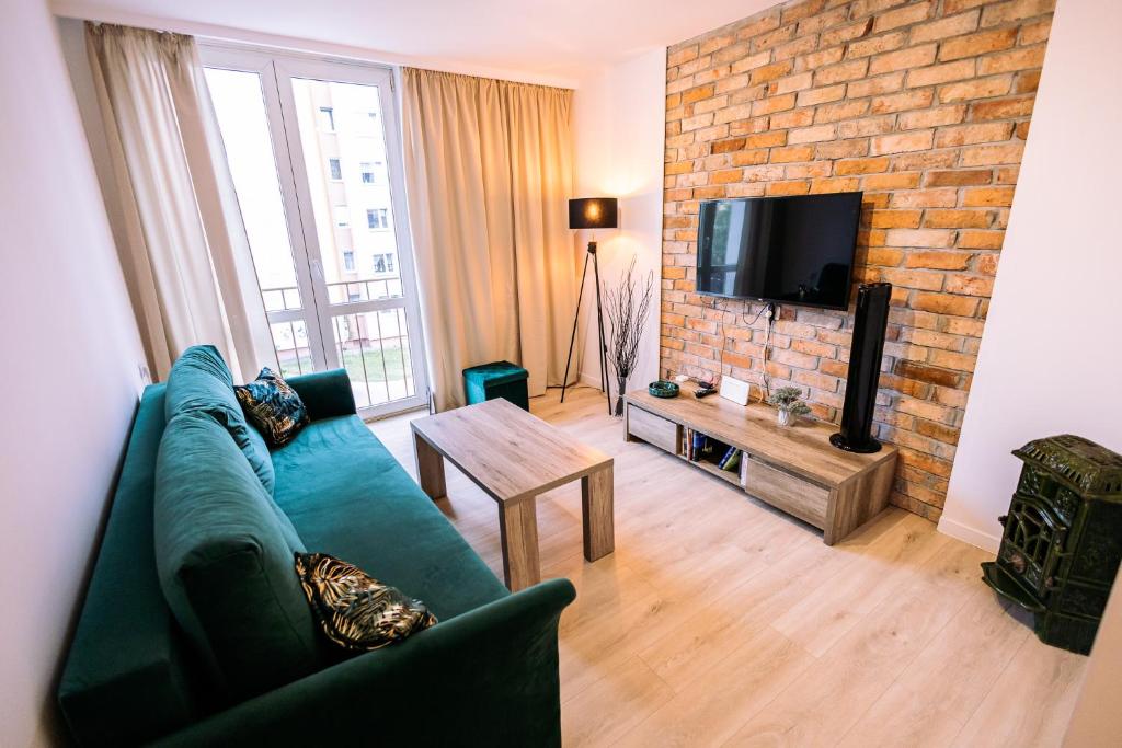 a living room with a green couch and a brick wall at Apartament Miejski Chill in Toruń