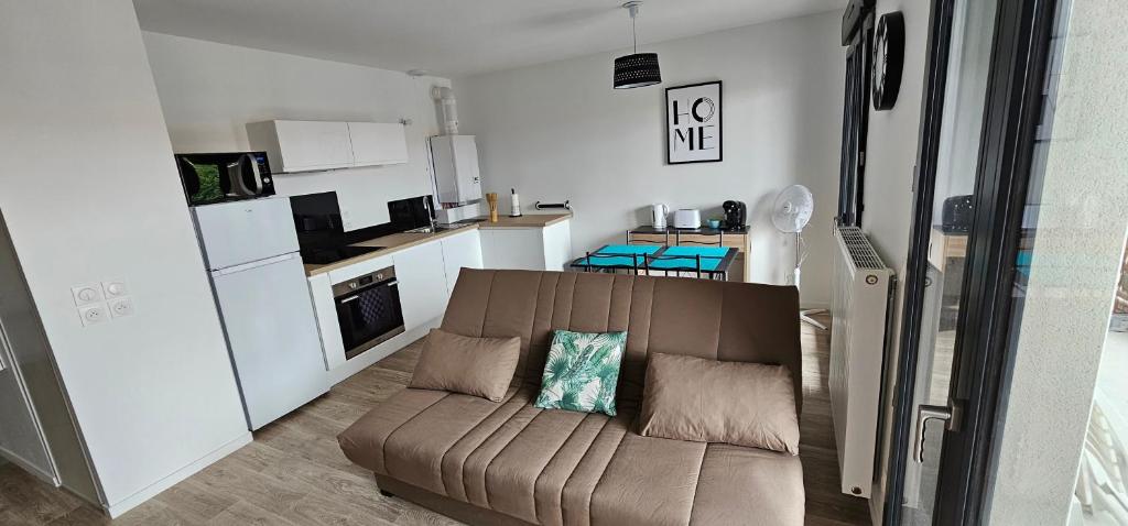 a living room with a couch and a kitchen at Location T2 neuf ecoquartier portes du Bassin D'ARCACHON in Biganos