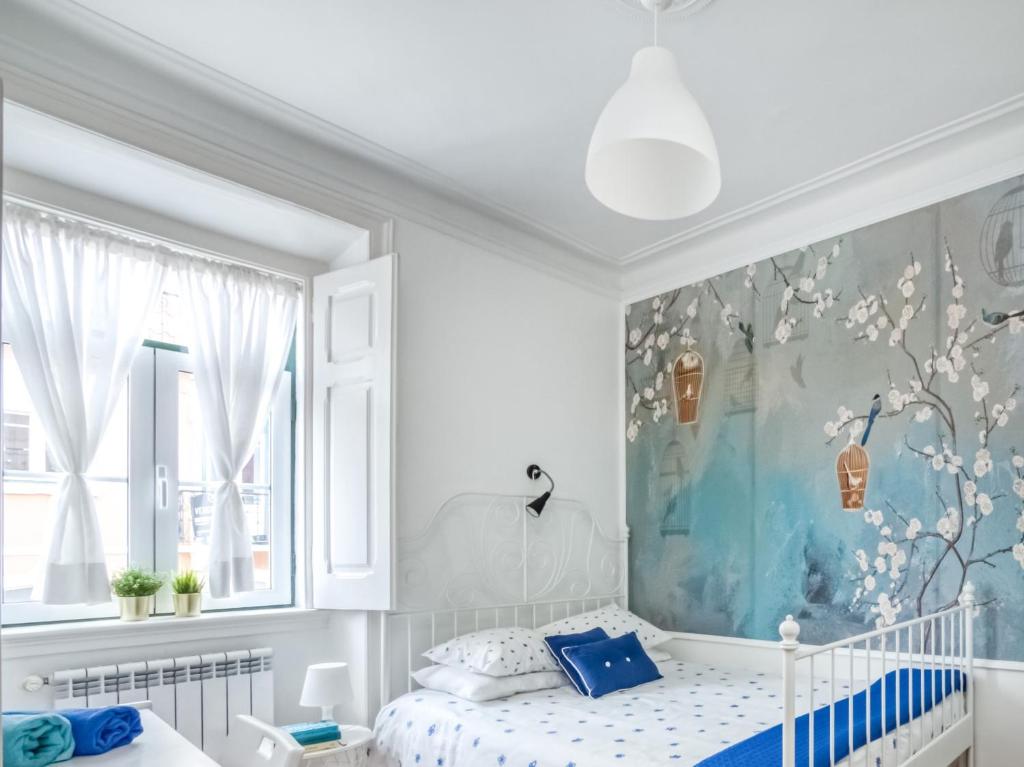 a white bedroom with a blue and white bed and a painting at Caza Latina in Lisbon