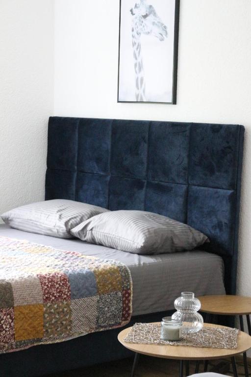 un lit avec une tête de lit bleue à côté d'une table dans l'établissement Blue Apartment, à Bihać