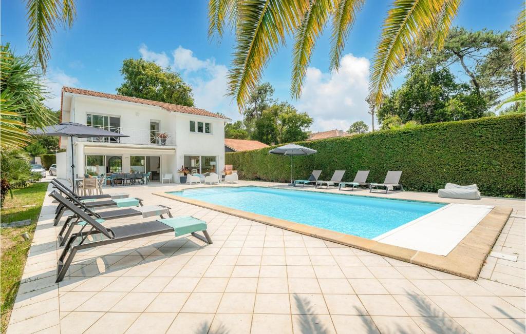 a swimming pool with chairs and a house at Beautiful Home In Lège-Cap-Ferret in Lège-Cap-Ferret