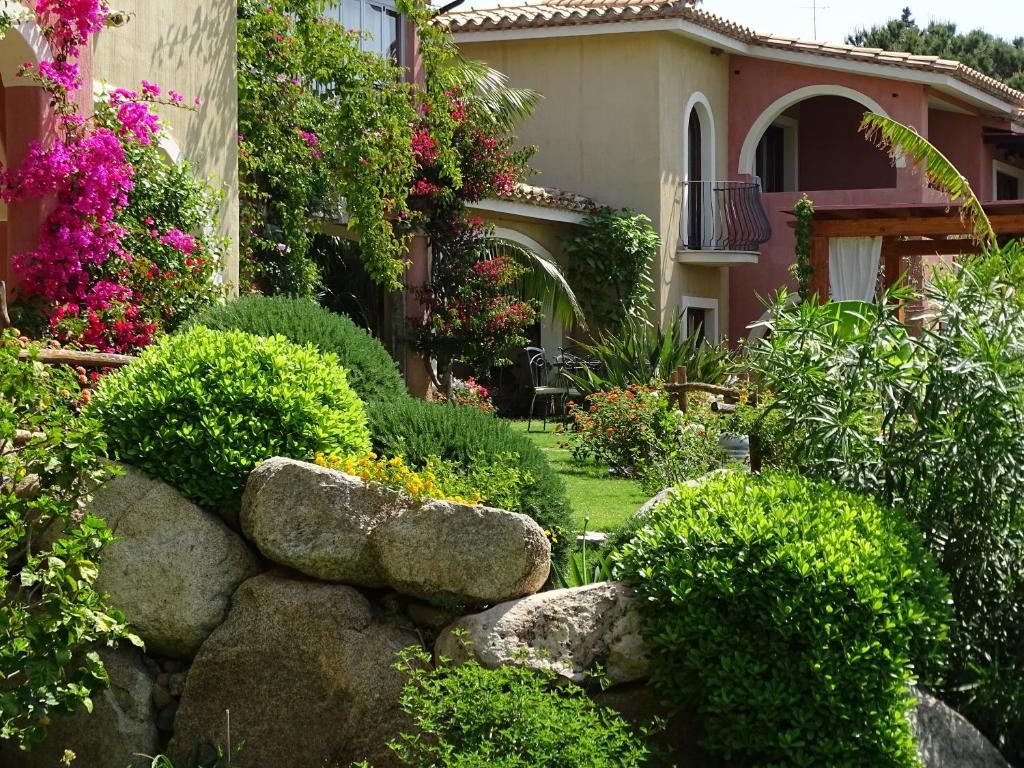 a garden with bushes and flowers in front of a house at Hotel Mariposas in Villasimius