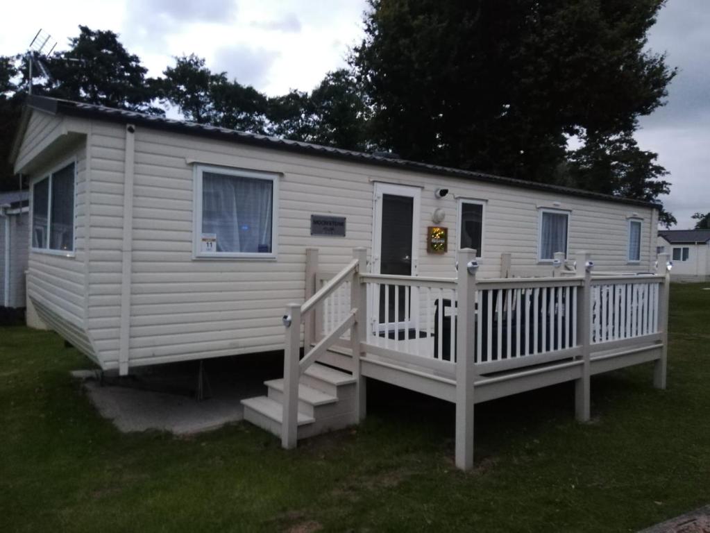 a white tiny house with a porch and a deck at Del's den lakeside weeley bridge 2bedroom in Weeley