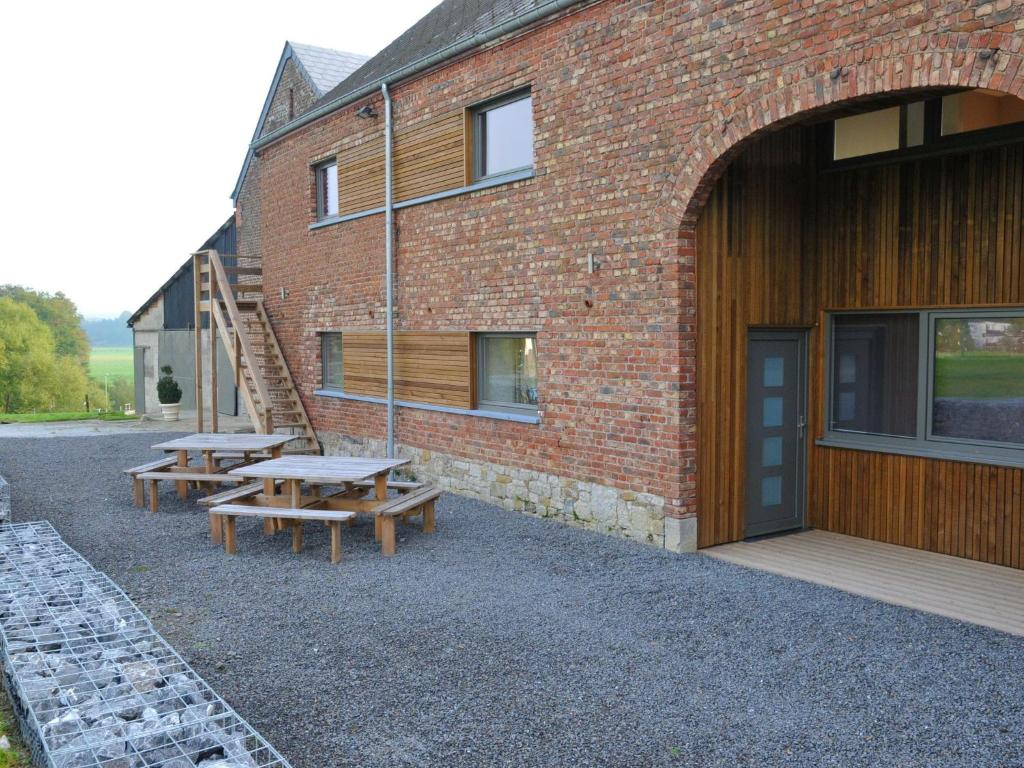 un edificio de ladrillo con dos mesas de picnic delante de él en Peaceful Holiday Home in Somme-Leuze with Sauna, en Noiseux