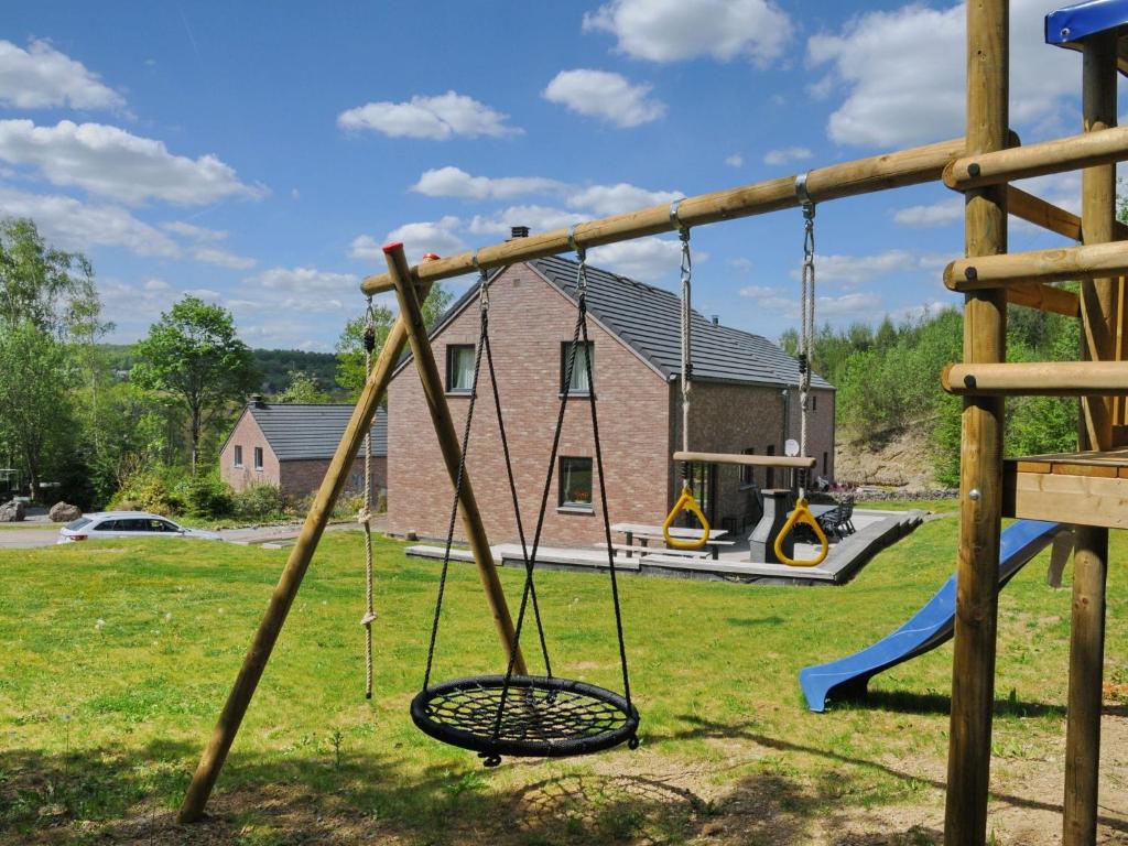 a swing set in a yard with a house at Beautiful Holiday Home in Barvaux-sur-Ourthe with Sauna in Barvaux