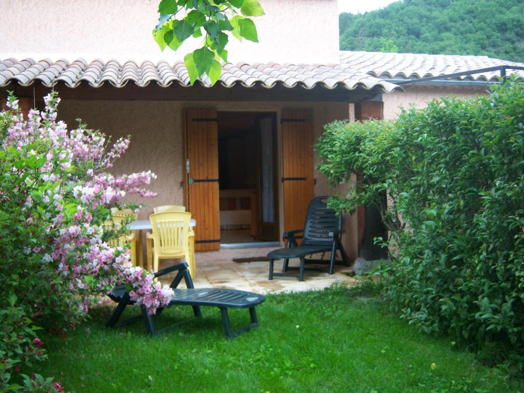 een patio met 2 stoelen en een bank in de tuin bij Lei Canissouns in Castellane