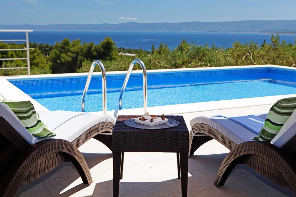 eine Terrasse mit 2 Stühlen und einem Pool in der Unterkunft Holiday Homes Oliva in Bol