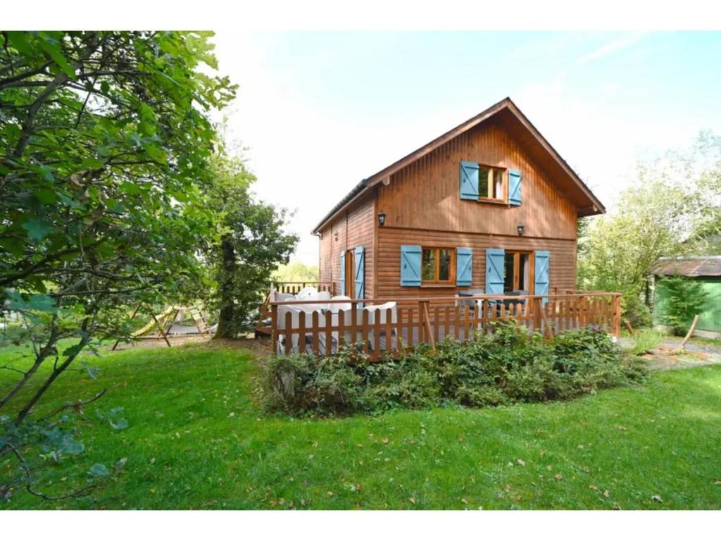 a large wooden house with a porch on a yard at Pleasant detached chalet with sauna near Durbuy in Biron