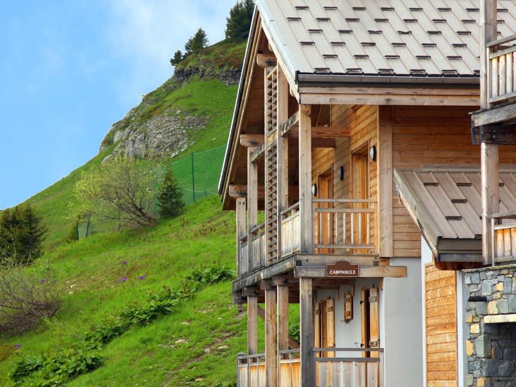 une maison en bois avec une colline en arrière-plan dans l'établissement Apartment in Flaine with Pool and Sauna, à Arâches-la-Frasse