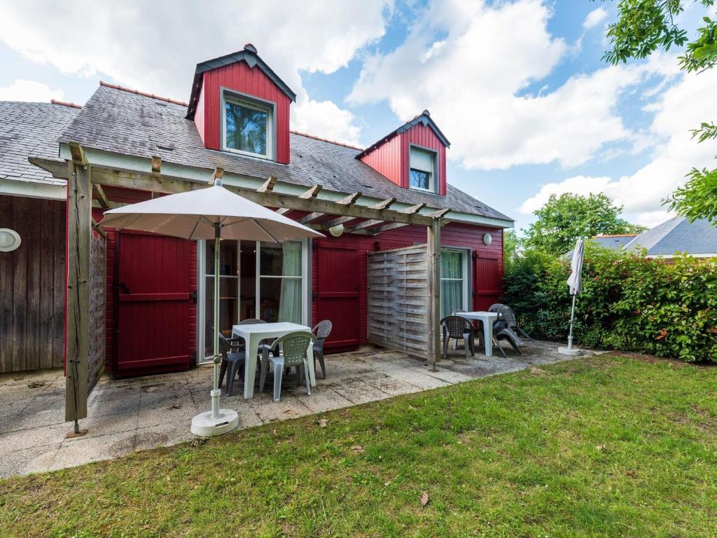 a red house with a patio with chairs and an umbrella at Beautiful maisonnette with included linen package in Saumur in Saumur