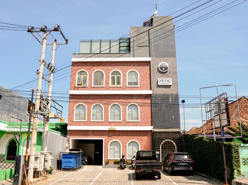 a tall brick building with cars parked in front of it at Ketje Luxury Capsule Lampung in Lampung