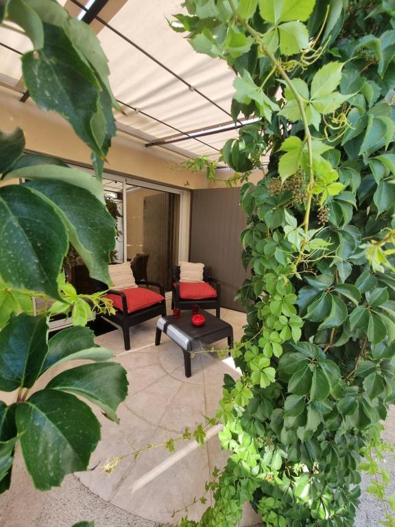 - un salon avec des fauteuils rouges et des plantes dans l'établissement Ma Charmante Maison En Provence, à Lançon-Provence
