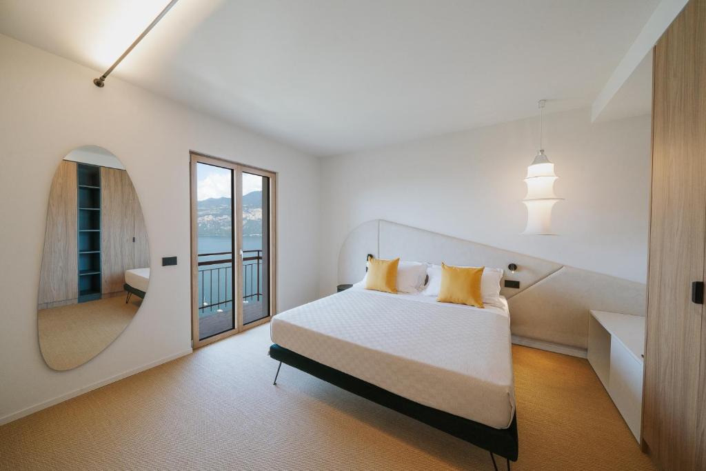 a white bedroom with a large bed and a mirror at VIEW Garda Lake in Brenzone sul Garda