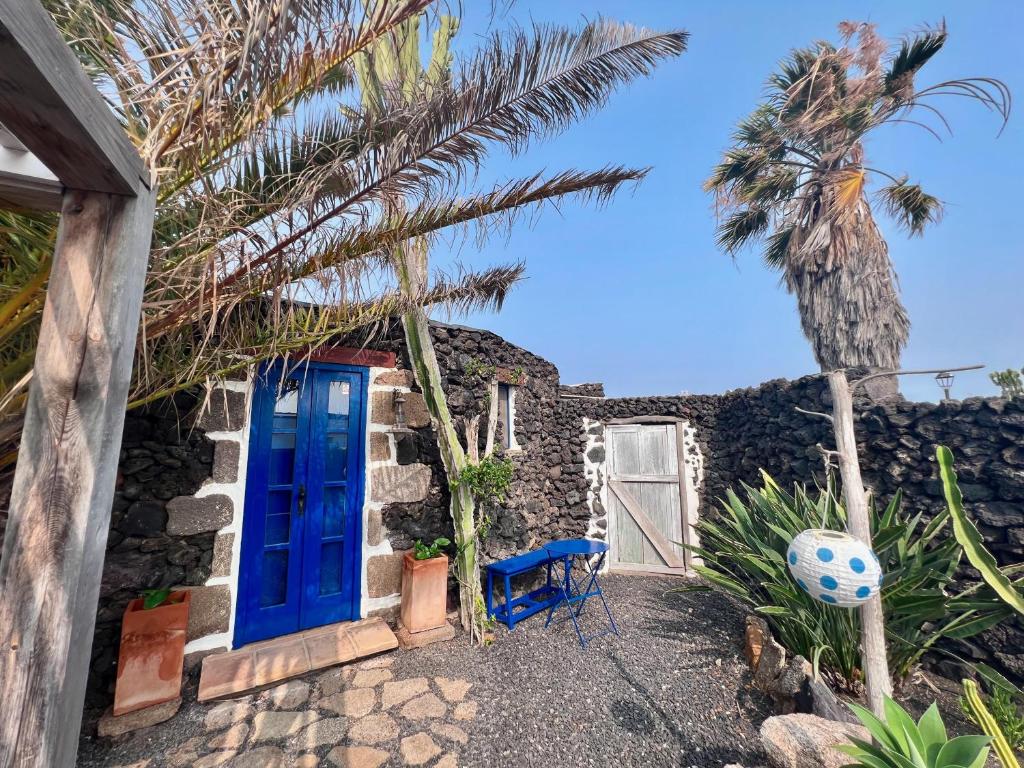 una casa con una puerta azul y una palmera en Charming Finca with beautiful private gardens, en Uga