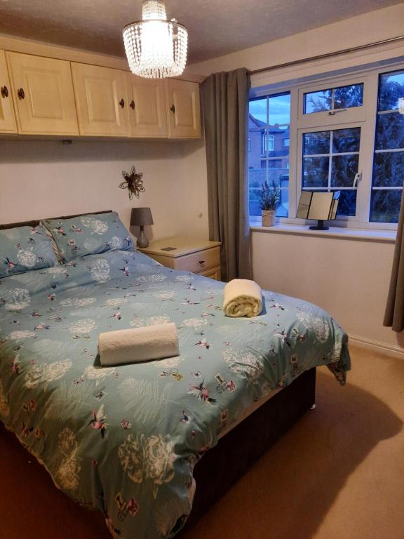 a bedroom with a bed with a blue comforter and a window at Redmire - 2 bed 1st floor flat overlooking green in Darlington