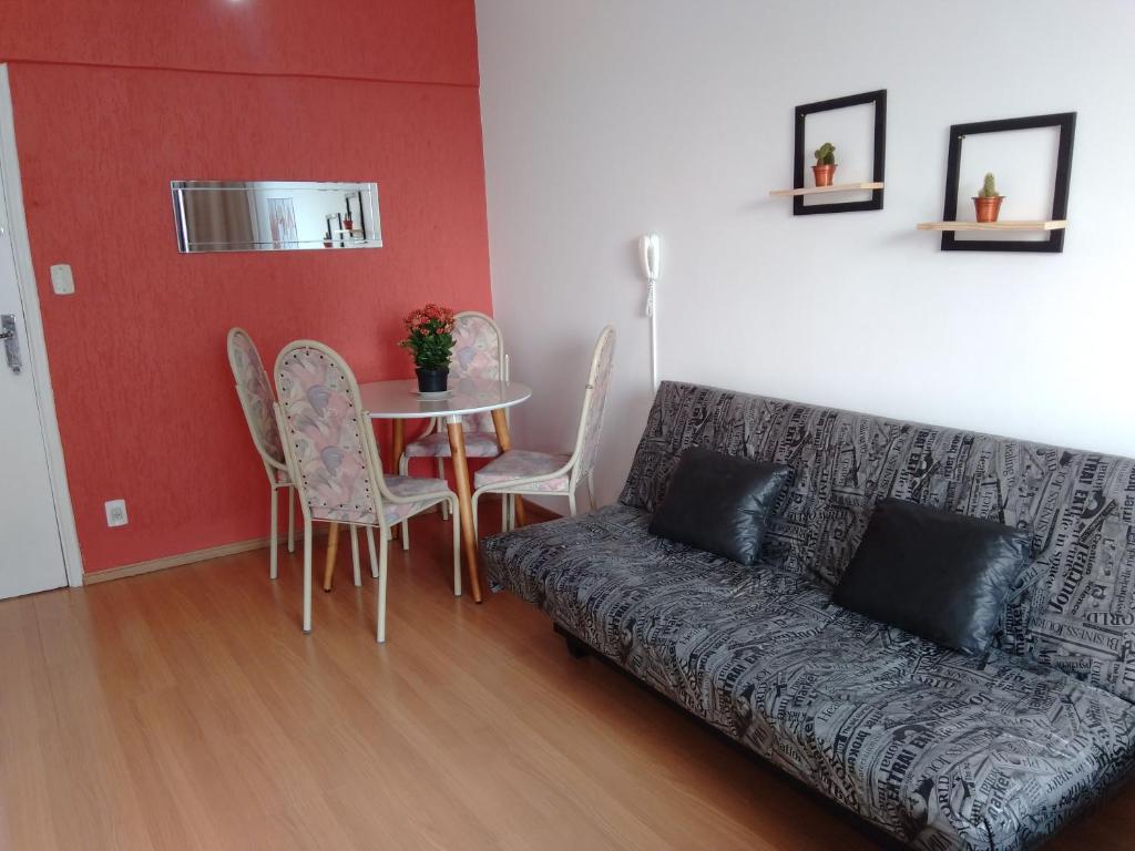 a living room with a couch and a table and chairs at Lindo Studio na Praia do Gonzaguinha II in São Vicente