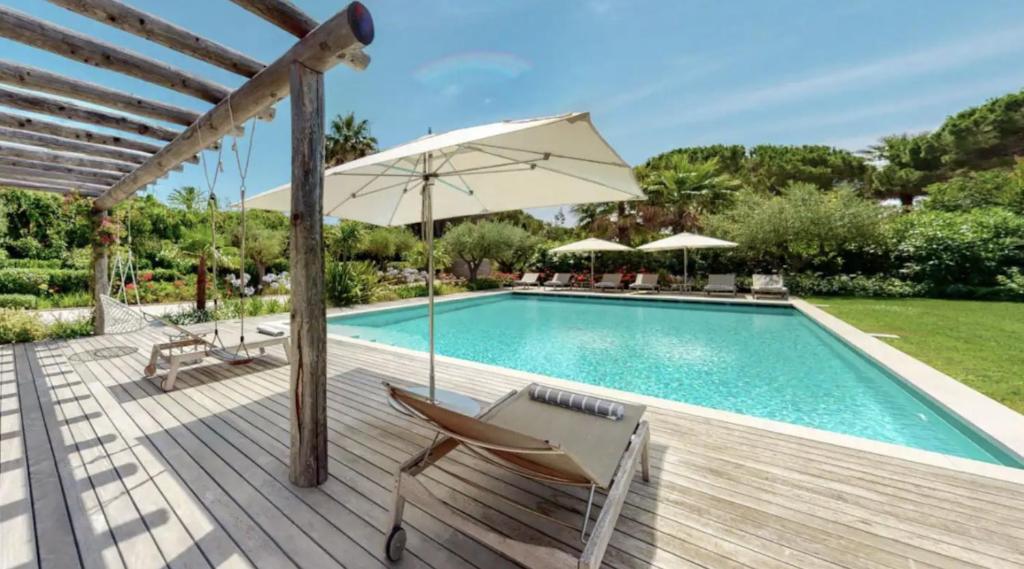 einen Pool mit einem Stuhl und einem Sonnenschirm auf einer Holzterrasse in der Unterkunft LUXURY VILLA 5BR in Cannes