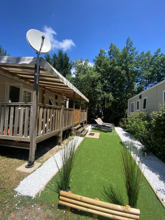 uma cabana de madeira com um alpendre e relva em Mobil-home Les Dunes de Contis em Saint-Julien-en-Born