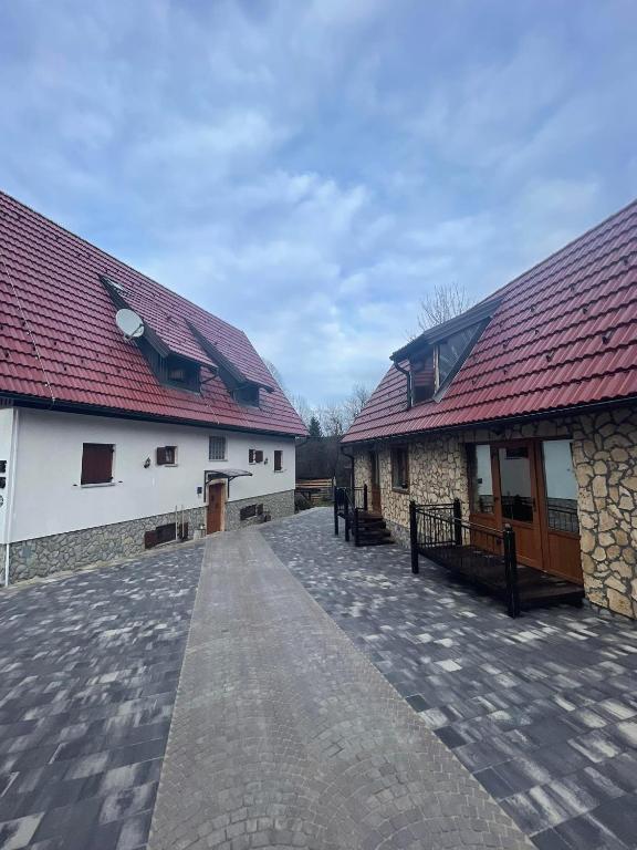 two buildings with red roofs and a walkway between them at Rustic Lodge Plitvice in Jezerce