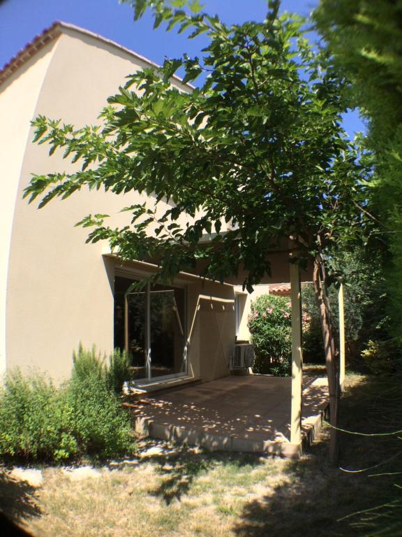 a house with a porch and a tree at Gite Du Lavoir in Saint-Geniès-de-Comolas
