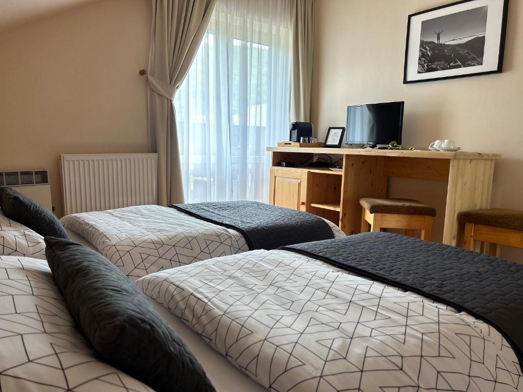 ein Hotelzimmer mit 2 Betten, einem Schreibtisch und einem TV in der Unterkunft Penzion v strani in Mýto pod Ďumbierom