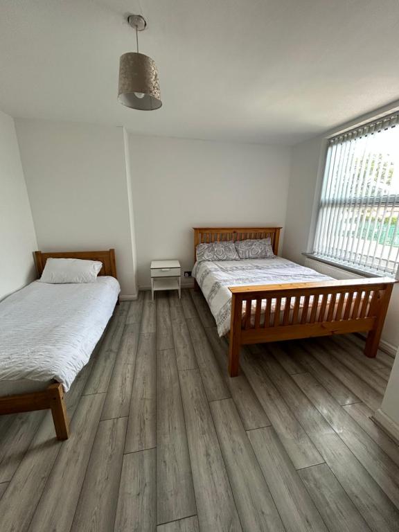 two beds in a room with wooden floors at Lovely 3 Bedroom Entire Home With Street Parking - Close to NEC, BHX Airport - Sleeps 6 Guests IDEAL FOR CONTRACTORS & FAMILIES in Birmingham